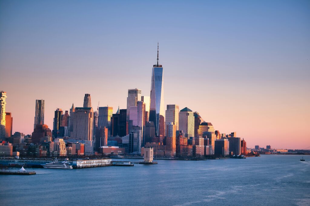 Stunning sunset view of the New York City skyline with calm waters.